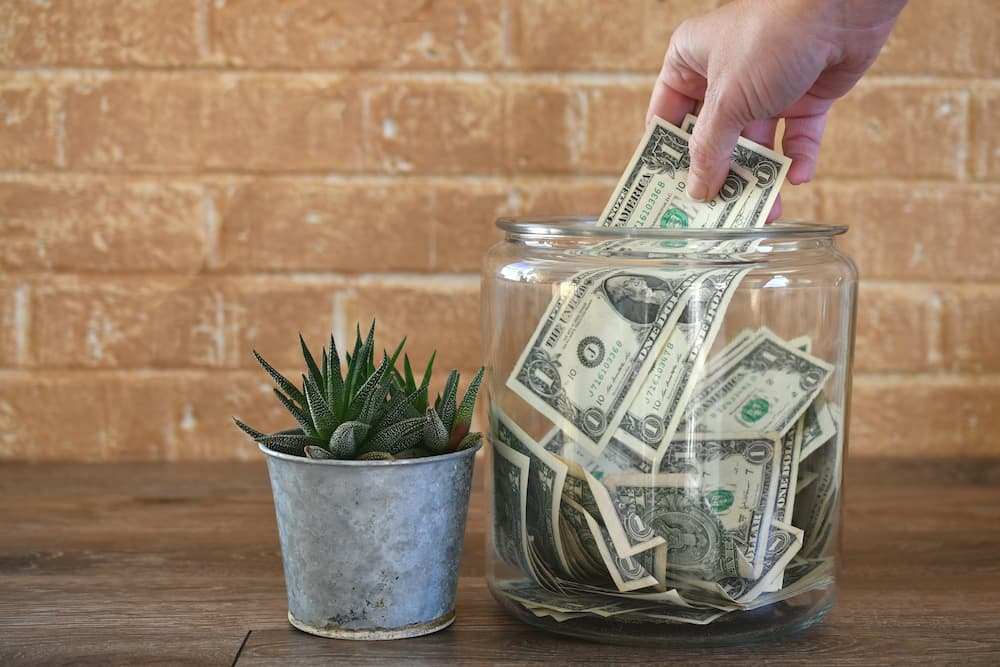 Person putting money into a clear jar