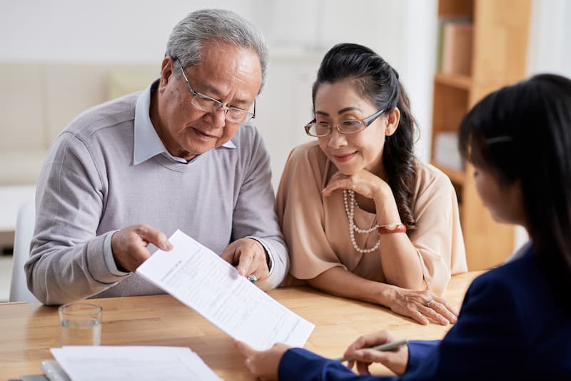 Senior Asian couple reviewing the terms of a reverse mortgage.