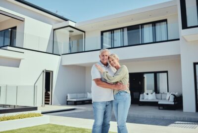 Senior couple standing in front of their Florida home after getting a reverse mortgage.