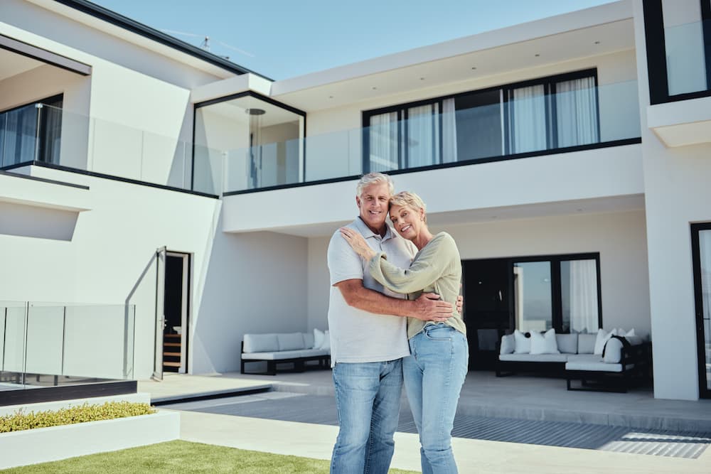 Senior couple standing in front of their Florida home after getting a reverse mortgage.